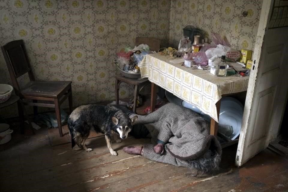 Un perro junto al cuerpo de una anciana asesinada dentro de una casa en Bucha, en las afueras de Kiev, Ucrania,