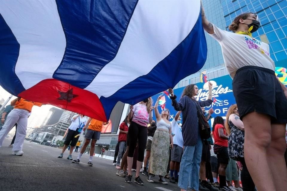 Activistas extienden una bandera de Cuba afuera de la sede de la Cumbre de las Américas en Los Ángeles.