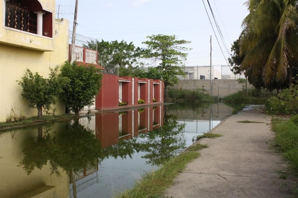 Con las lluvias, el agua queda estancada en la calle que colinda con una barda de la refinería.