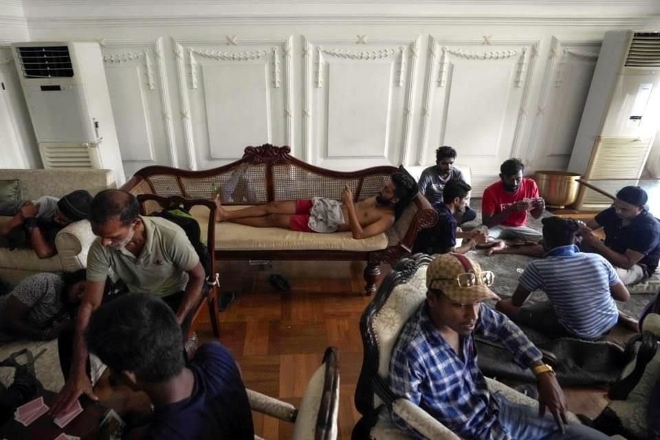 Manifestantes descansan y juegan cartas en la residencia oficial de Sri Lanka, tras tomarla por asalto el domingo.