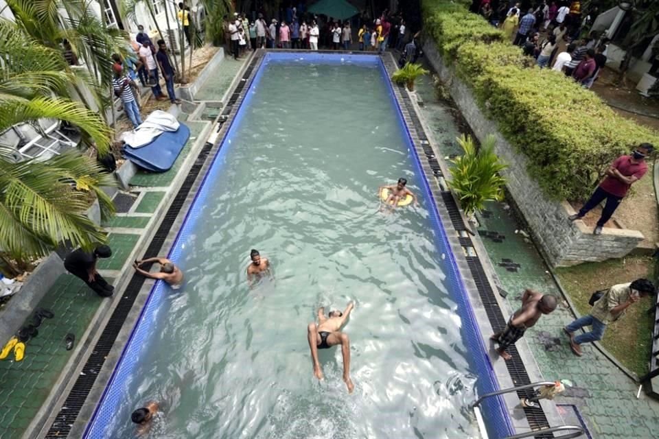 Algunas personas nadan este domingo en el agua turbia de la piscina del palacio presidencial de Sri Lanka.