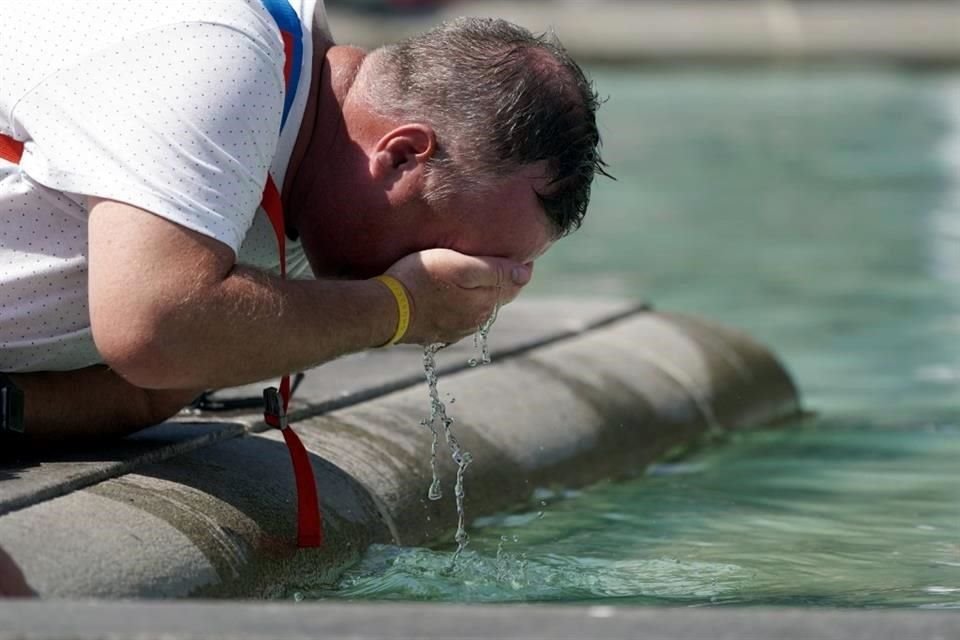 Un hombre se refresca con agua de una fuente en la Plaza de Trafalgar, en Londres.