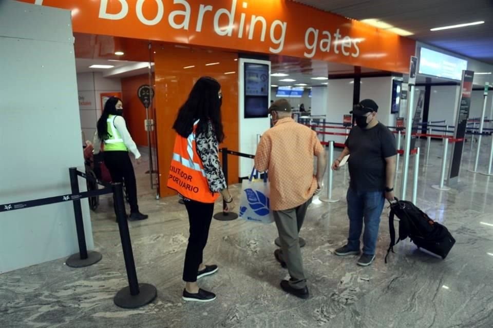 Personal de chaleco naranja orienta sobre cómo llegar al filtro de seguridad para pasajeros.