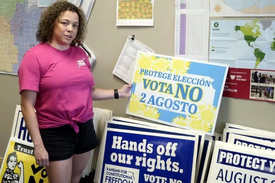 Jessica Porter muestra carteles que llaman a la gente a votar en contra de la enmienda constitucional para restringir el aborto en Kansas.