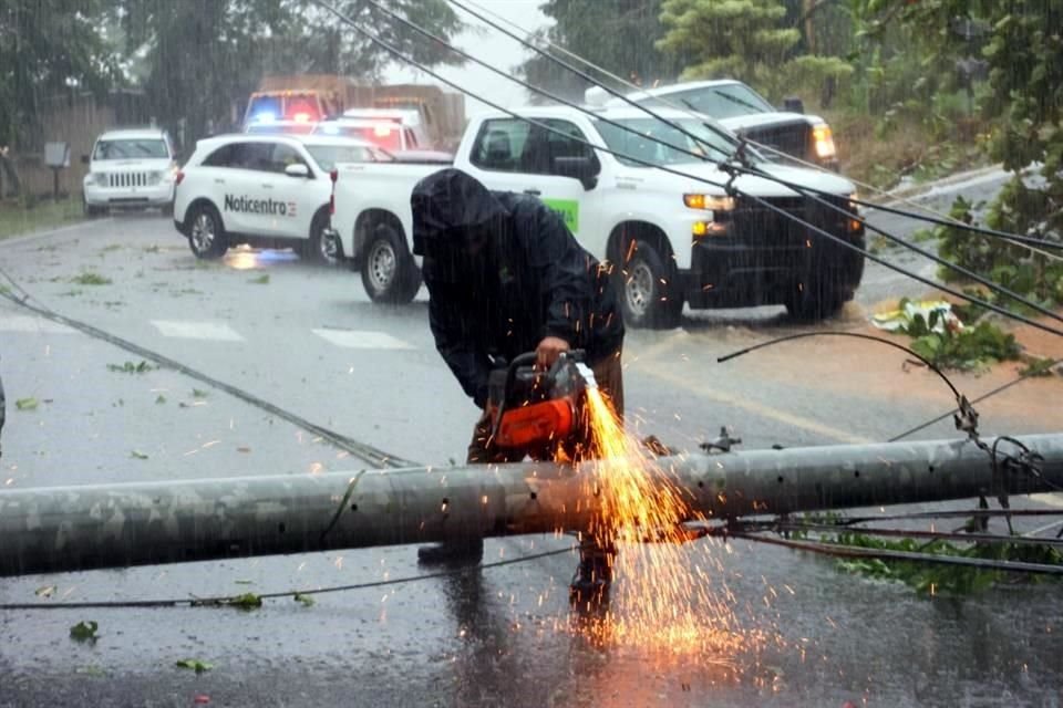 un hombre corta un poste de luz que cayó y bloqueó un camino en Cayey, Puerto Rico.