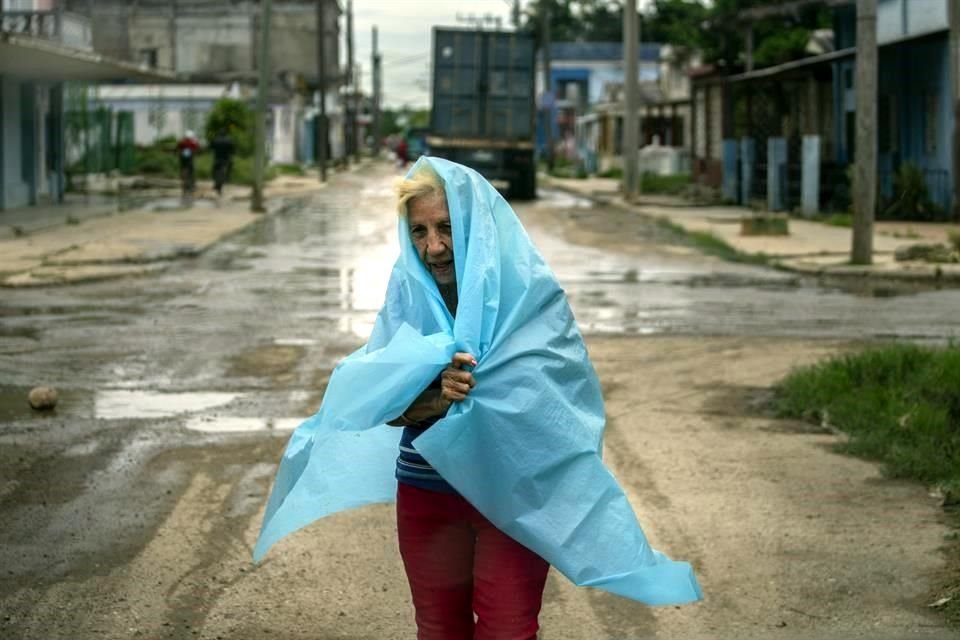 Una residente de Batabano, Cuba, se protege de las lluvias con una manta de plástico.