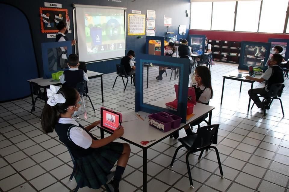 A los alumnos los separa una pantalla de acrílico. En la clase hay presencia física y virtual de los estudiantes.