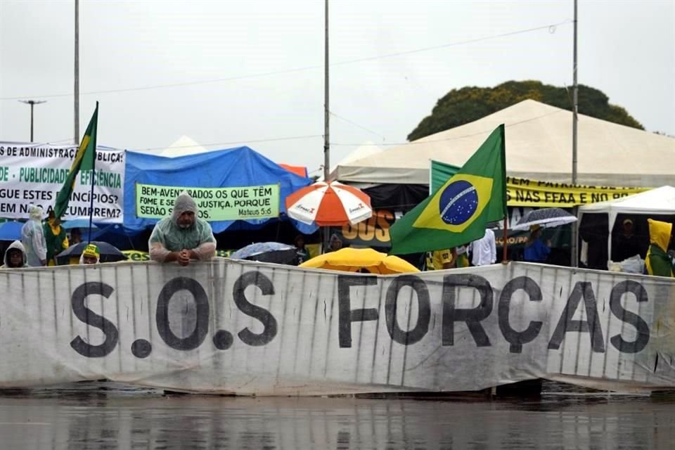 Partidarios del Presidente saliente Jair Bolsonaro exhiben una pancarta con un mensaje que pide ayuda a las Fuerzas Armadas.