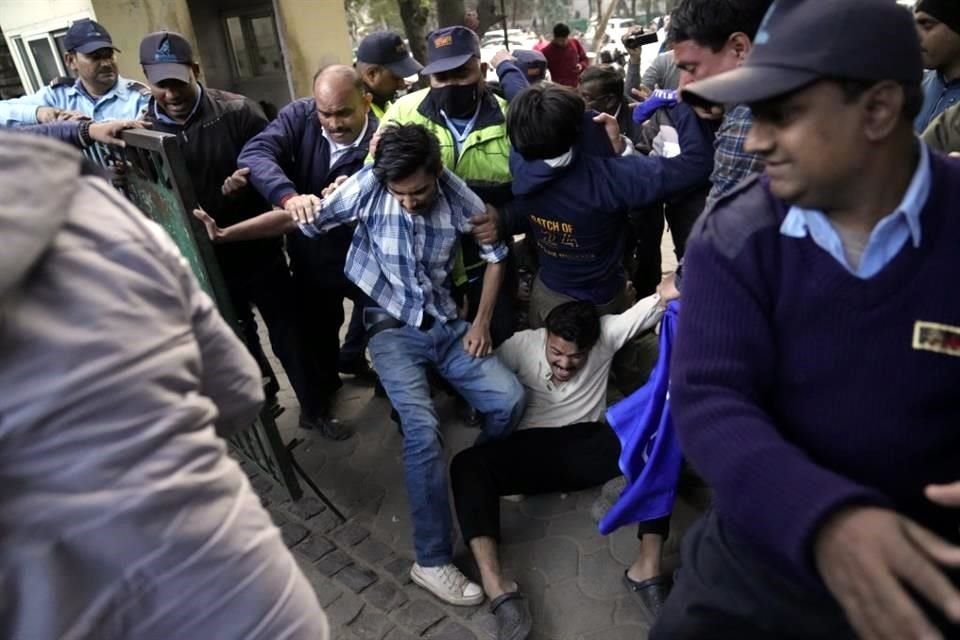 Los estudiantes que querían proyectar un documental de la BBC se resisten a ser escoltados fuera del campus por los guardias de seguridad de la Universidad de Delhi.