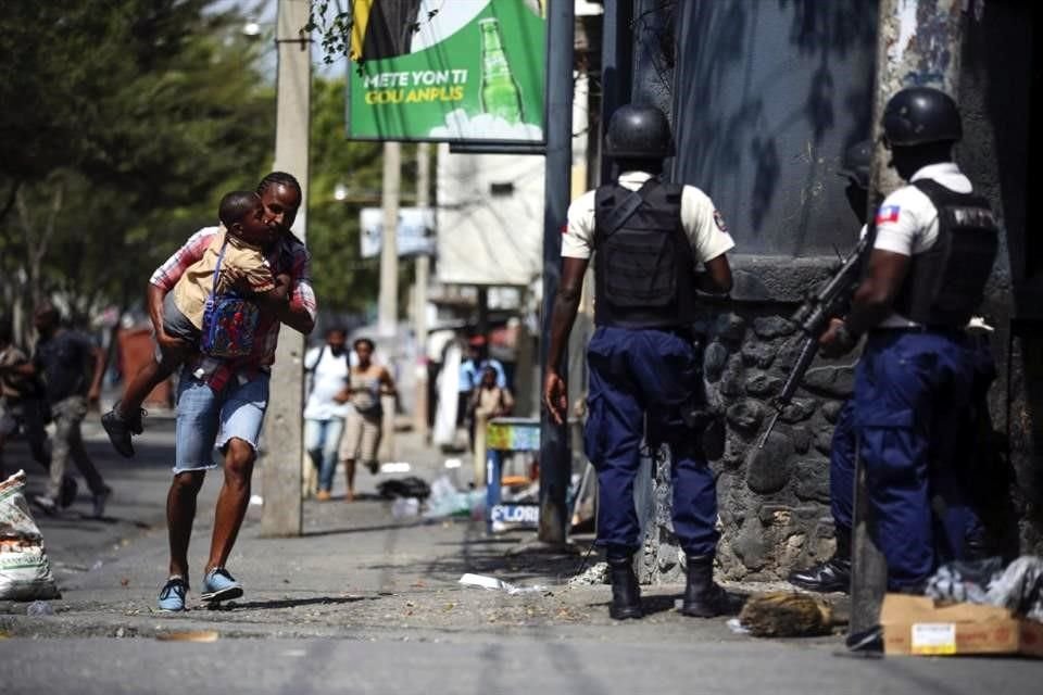 Un padre corre con su hijo frente a agentes de la policía, en Puerto Príncipe, Haití.