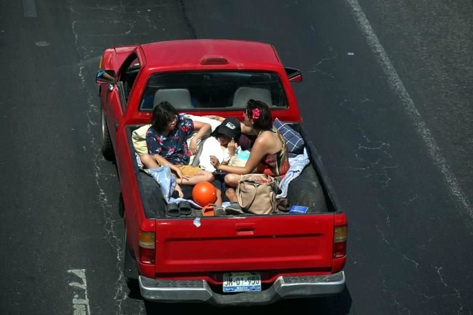 Hasta en las cajas de las camionetas va la gente a vacacionar, sin importar el calor ni el fuerte sol.