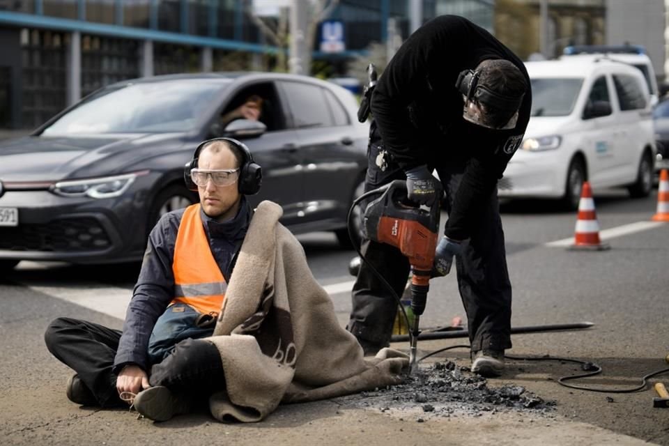 Un Policía retira el pavimento alrededor de la mano de un activista, pegada al suelo en protesta a la política climática del Gobierno alemán.