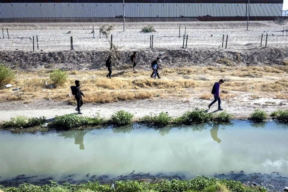 Migrantes hondureños caminan por el lado estadounidense del Río Grande y pasan por un campamento de migrantes vacío después de cruzar desde México el 13 de mayo a El Paso, Texas.