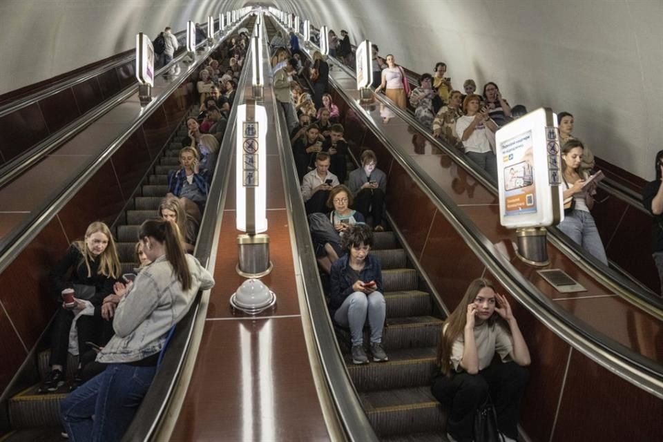 Decenas de personas aguardan en las escaleras eléctricas de una estación del metro usada como refugio durante un ataque con cohetes rusos en Kiev.