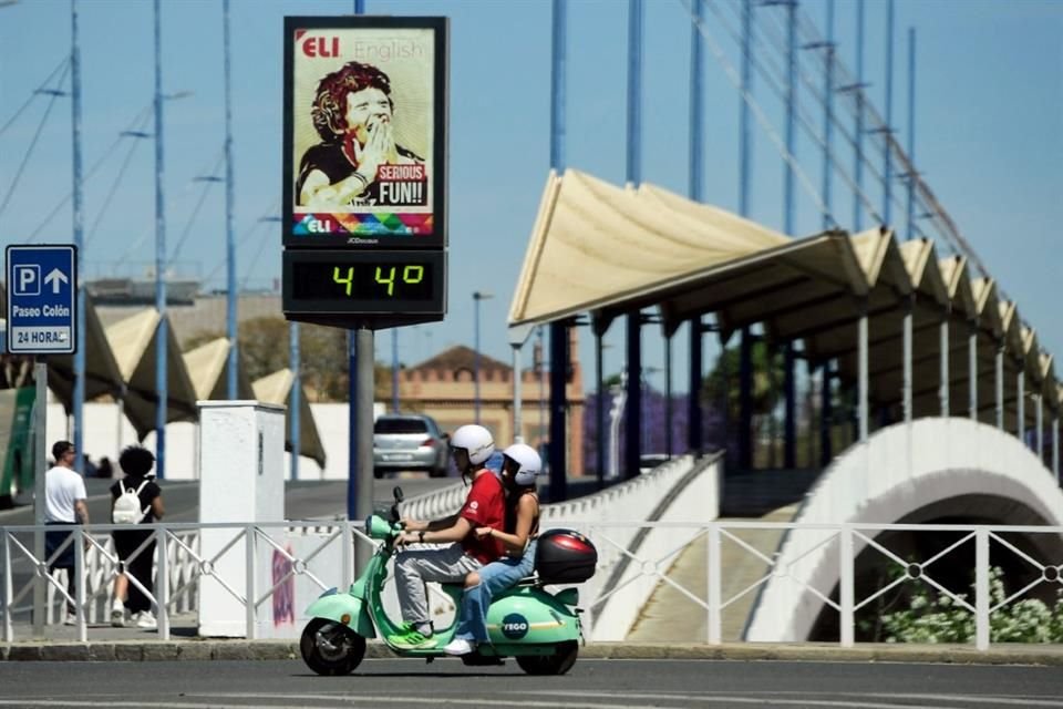 Una pareja maneja en una motoneta junto a un termométro en la calle que indica 44 grados centígrados de temperatura, el 26 de abril, en España.