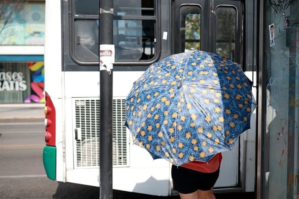 Ciudadanos esperan los camiones bajo el sol.