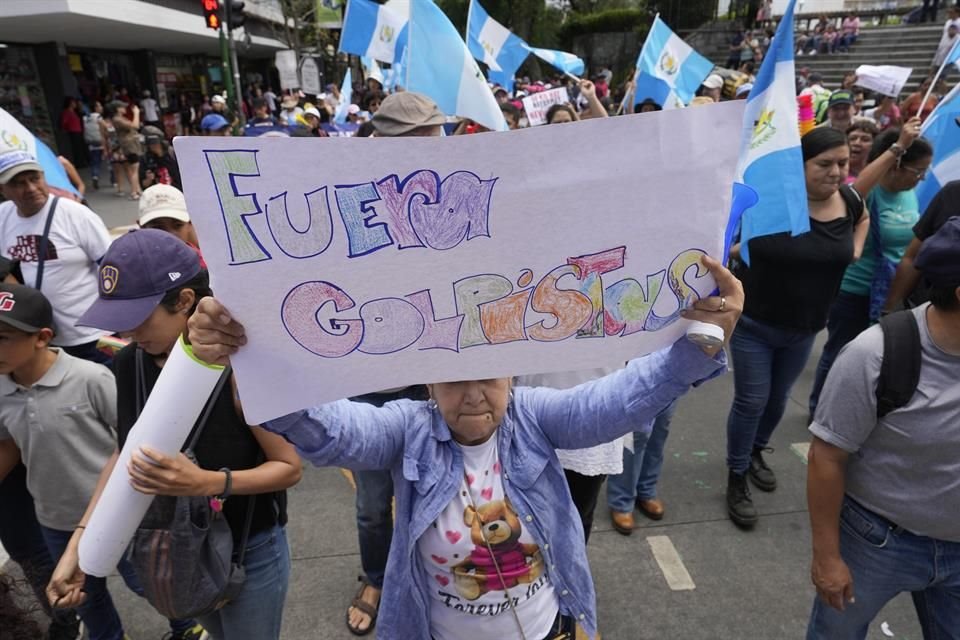 Una mujer sostiene un cartel durante una marcha contra las acciones legales emprendidas por la Fiscalía General contra el partido Movimiento Semilla en Guatemala.