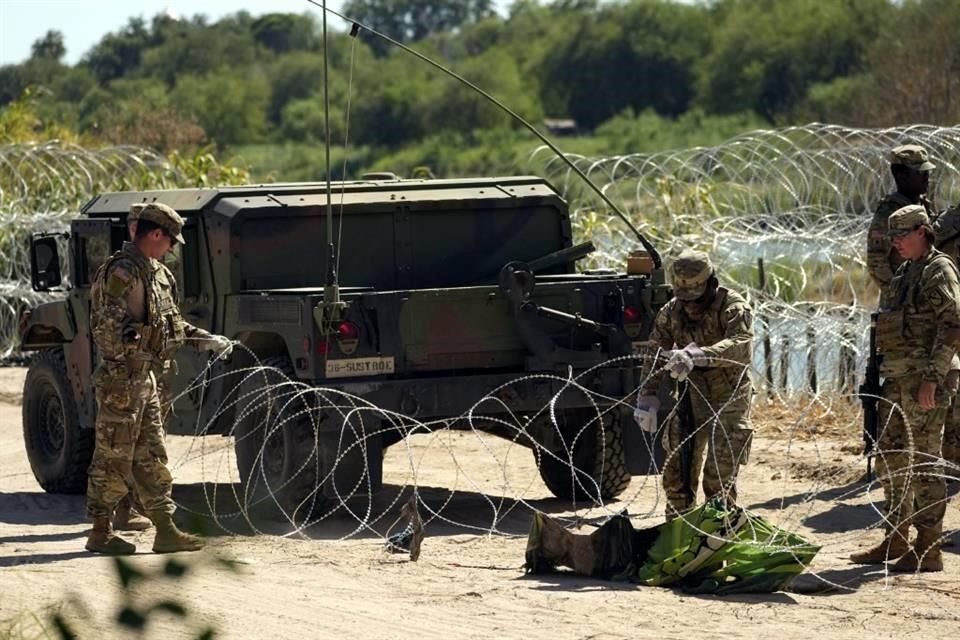 Guardias estadounidenses colocan alambre de púas en la frontera para evitar que migrantes pasen a ese país.