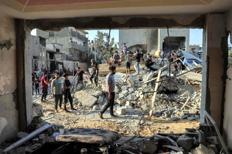 La gente se reúne junto a los escombros de un edificio después de un ataque aéreo israelí en Rafah.