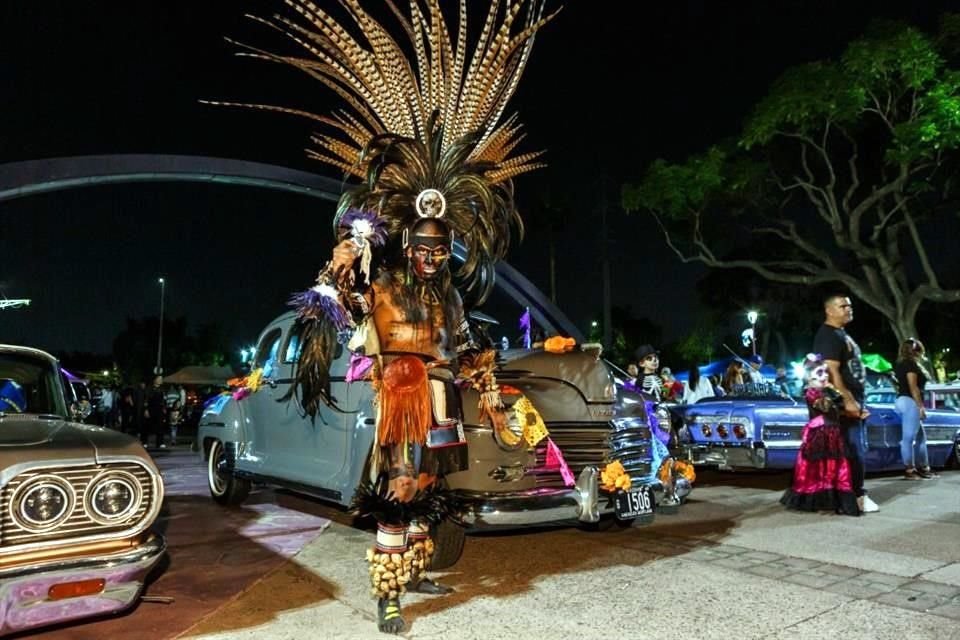 Con un gran penacho de plumas y cascabeles en sus pies, Marco camina entre los autos como un guerrero azteca después de danzar.