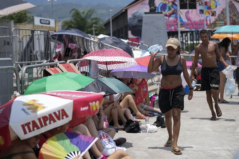 En Brasil, vendedores ambulantes ofrecen botellas de agua a swifties, quienes bajo el sol esperan el inicio del show de Taylor Swift.