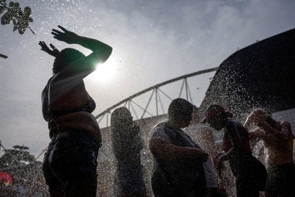 Los fanáticos de la cantante estadounidense Taylor Swift se refrescan mientras hacen cola afuera del Estadio Olímpico Nilton Santos antes del concierto.