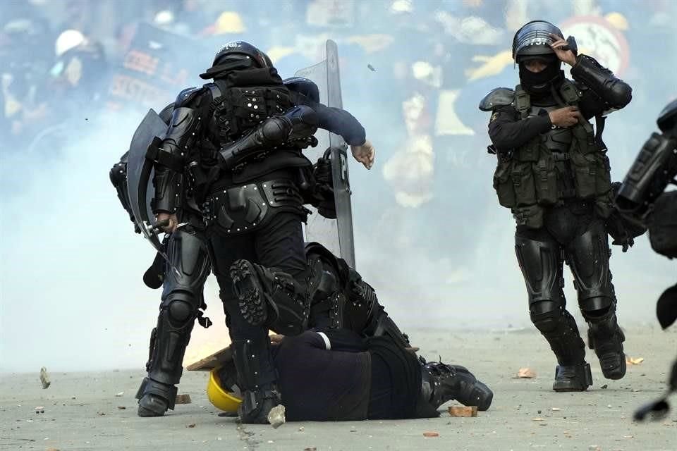 Un agente antidisturbios patea a un manifestante durante una protesta en Bogotá, Colombia.