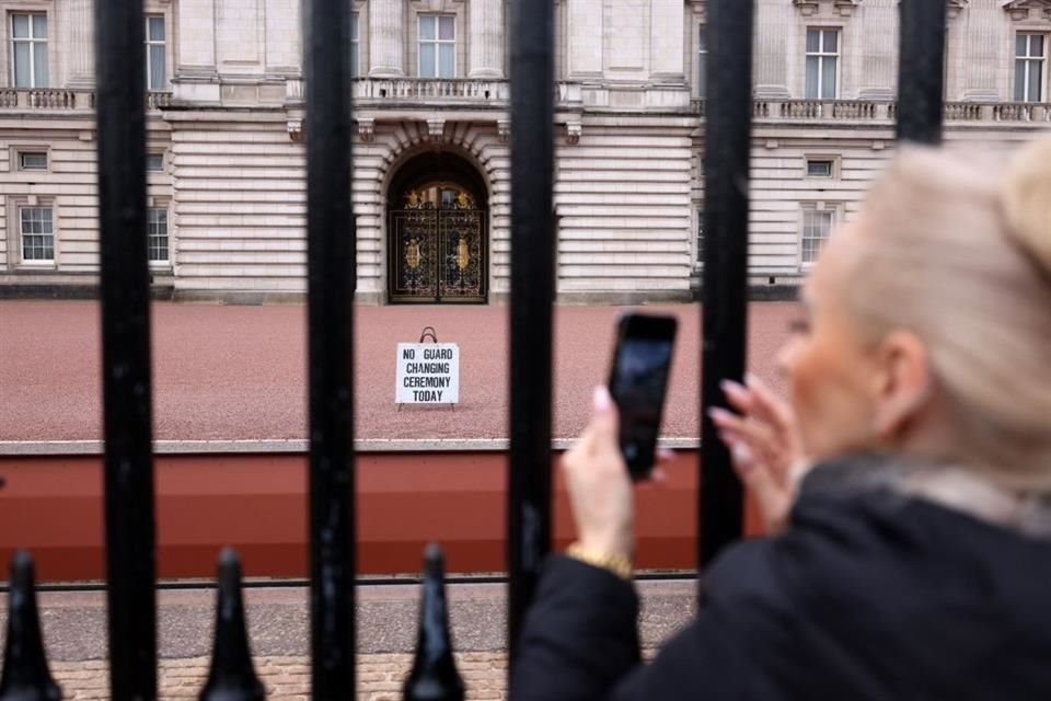 Los turistas se reúnen frente a las puertas del Palacio de Buckingham en Londres tras el padecimiento de Carlos III.