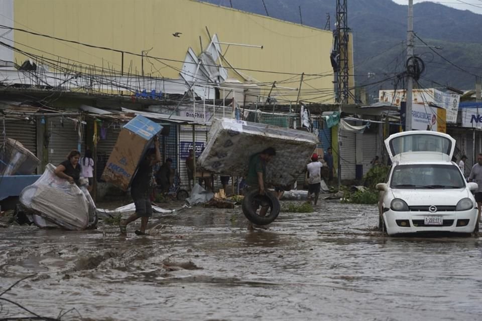 FILE - People carry away a mattress, a television monitor and a bicycle from a store at a shopping mall after Hurricane Otis ripped through Acapulco, Mexico, Oct. 25, 2023.