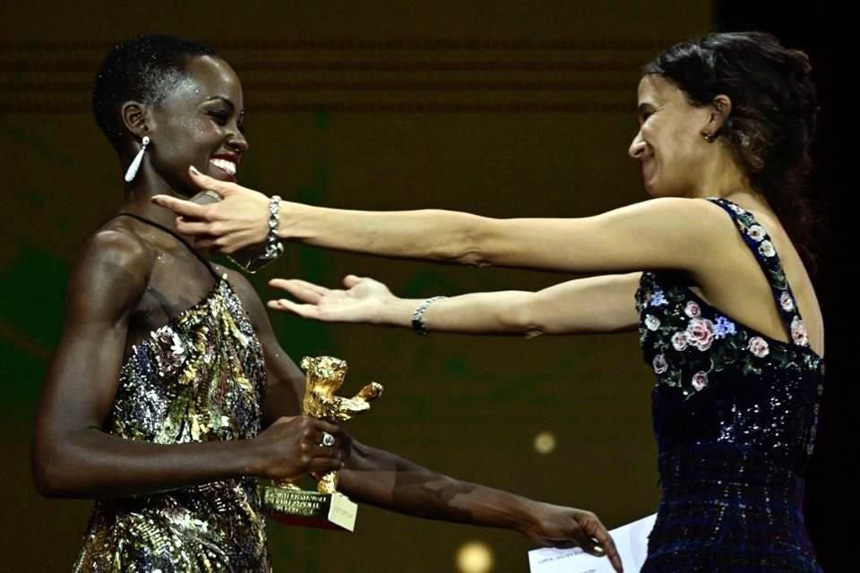 La cineasta y actriz franco-senegalesa Mati Diop (R) acepta el Oso de Oro a la Mejor Película por 'Dahomey' de la actriz keniano-mexicana y presidenta del Jurado Internacional 2024 Lupita Nyong'o.