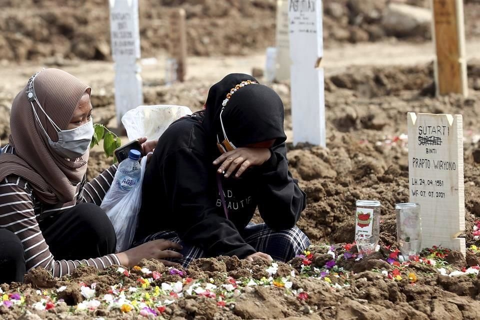 Dos mujeres visitan la tumba de un familiar en el Cementerio de Rorotan, Indonesia, el cual está reservado para víctimas de Covid-19.