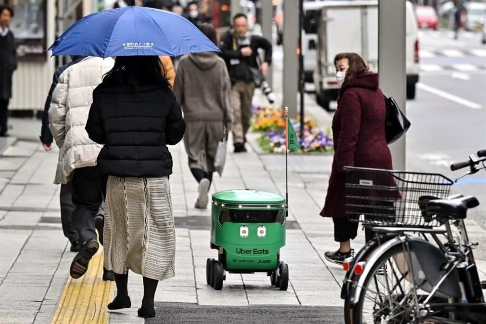 Peatones ven pasar al robot de entregas de Uber Eats.