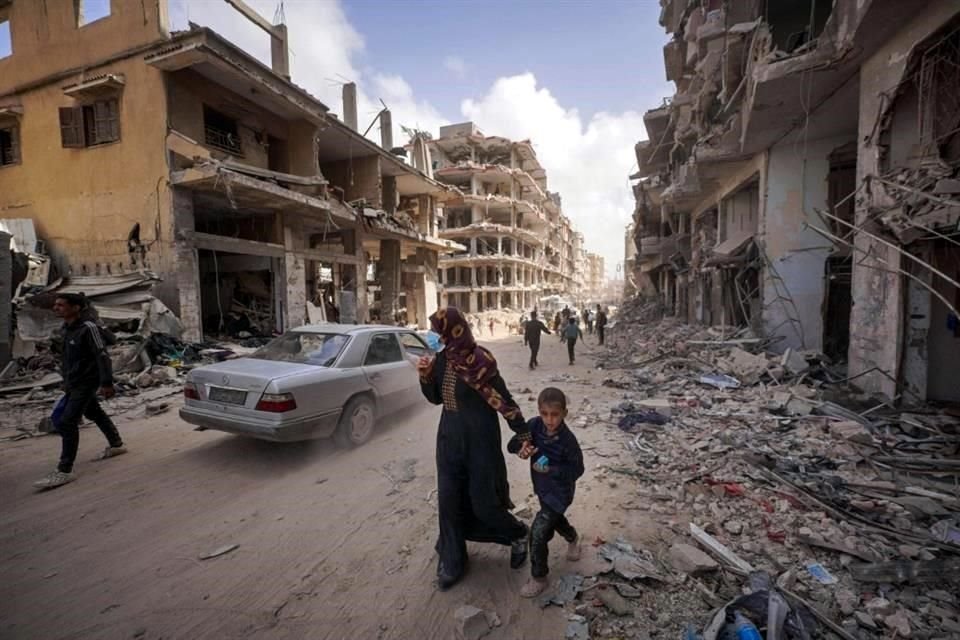 Los palestinos caminan junto a los escombros de las casas destruidas por el bombardeo israelí en Khan Yunis.