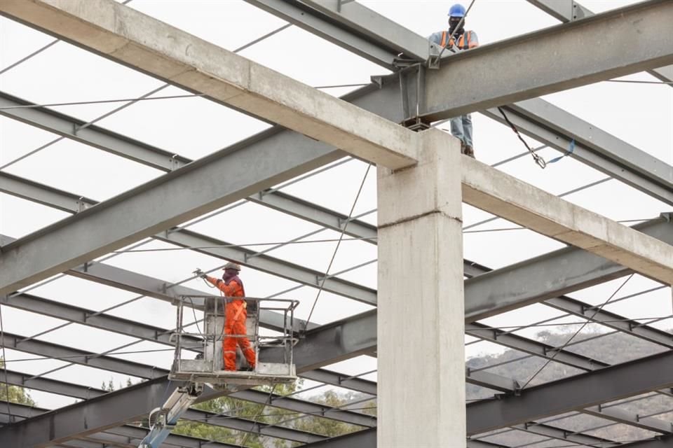 Trabajadores de la construcción pintan las vigas en el edificio de cocheras.