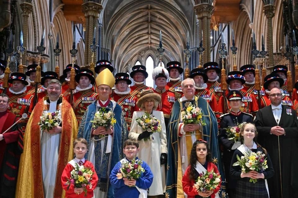 La Reina lució un elegante abrigo largo de lana color crema adornado con broches de flores doradas y azules.