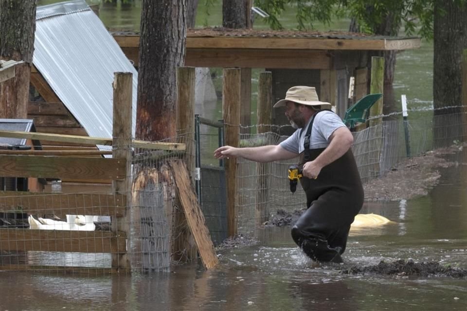 Un hombre hace preparaciones para proteger a sus animales tras el desbordamiento de un río en Liberty, Texas.