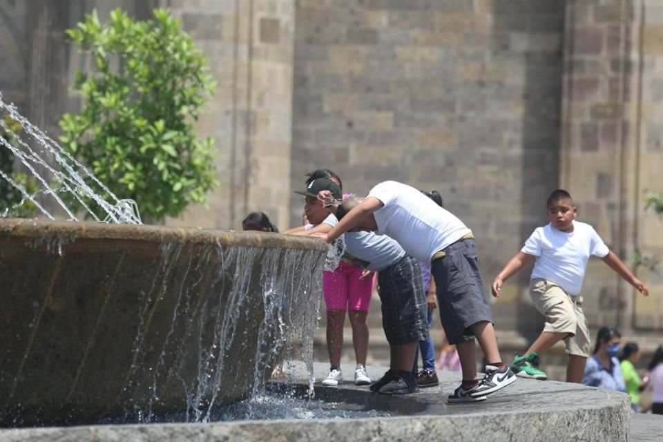 Niños se refrescan en la fuente de Plaza Guadalajara, ante altas temperaturas.