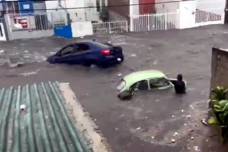 Un vecino detiene su vehículo para que no se lo lleve la corriente mientras otro es arrastrado.
