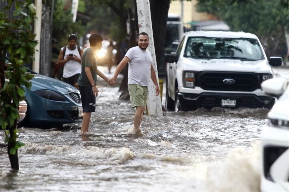 Al mal tiempo, buena cara. Pese al nivel del agua en Avenida Tuzanía, algunas personas trataron de ayudarse a cruzar las calles.