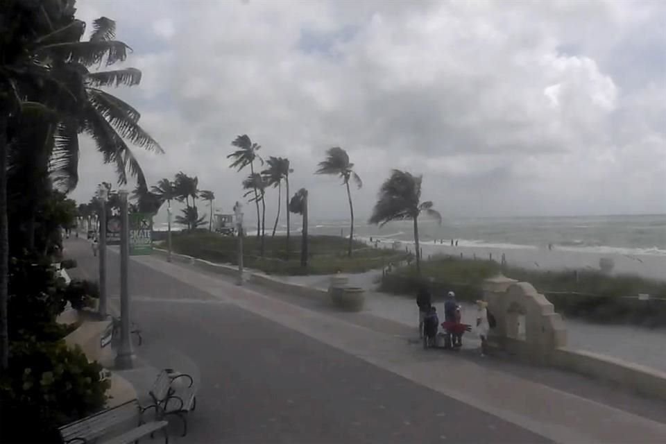 Gente camina por una playa mientras la tormenta tropical 'Debby' avanza por el Golfo de México hacia Florida el 4 de agosto de 2024 en Hollywood, Florida.