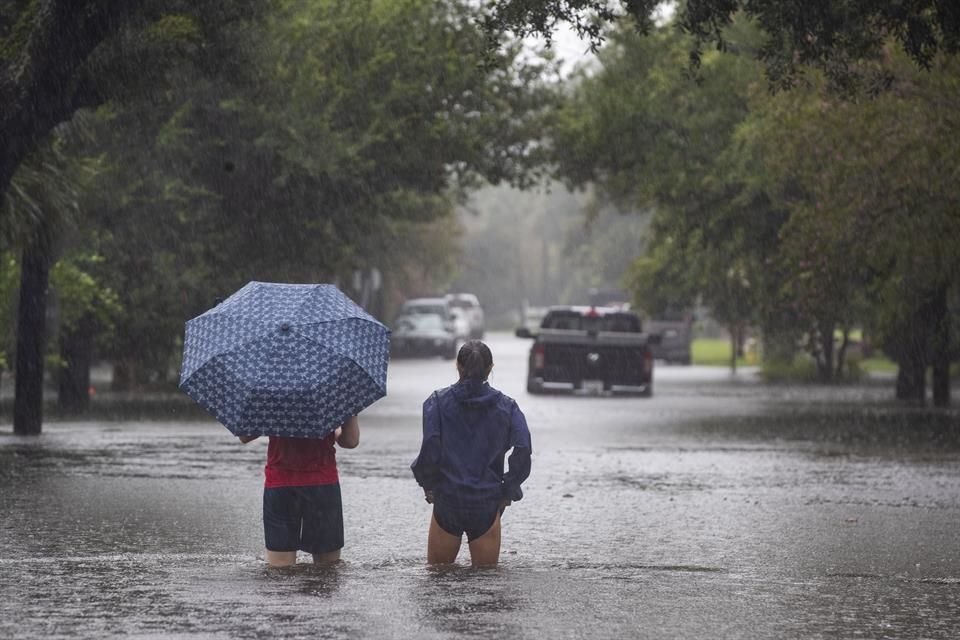 Personas en medio de una calle inundada en Charleston tras el paso de la tormenta 'Debby'.