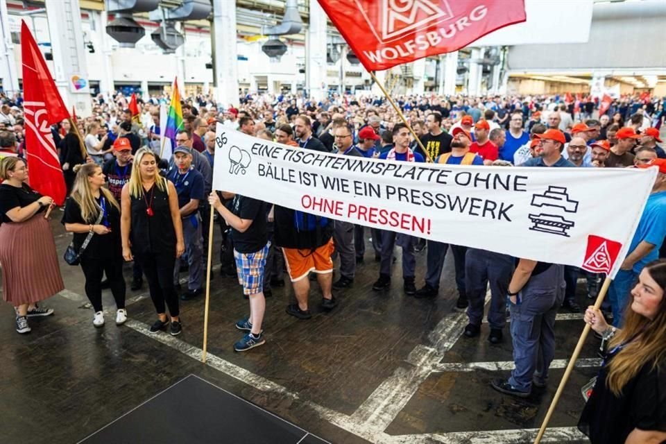 Empleados de Volkswagen sostienen una pancarta que dice 'Una mesa de ping-pong sin pelota es como una planta de prensado sin prensas' en una protesta al inicio de una asamblea general de la compañía en Wolfsburg.