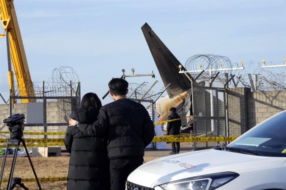 Familiares de víctimas de accidente observan el lugar del incendio de avión desde el exterior del Aeropuerto Internacional de Muan en Muan, Corea del Sur.