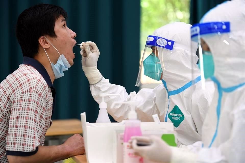Un trabajador médico toma una muestra de hisopado de un hombre en un sitio de pruebas para la detección de COVID-19, en Nanjing.