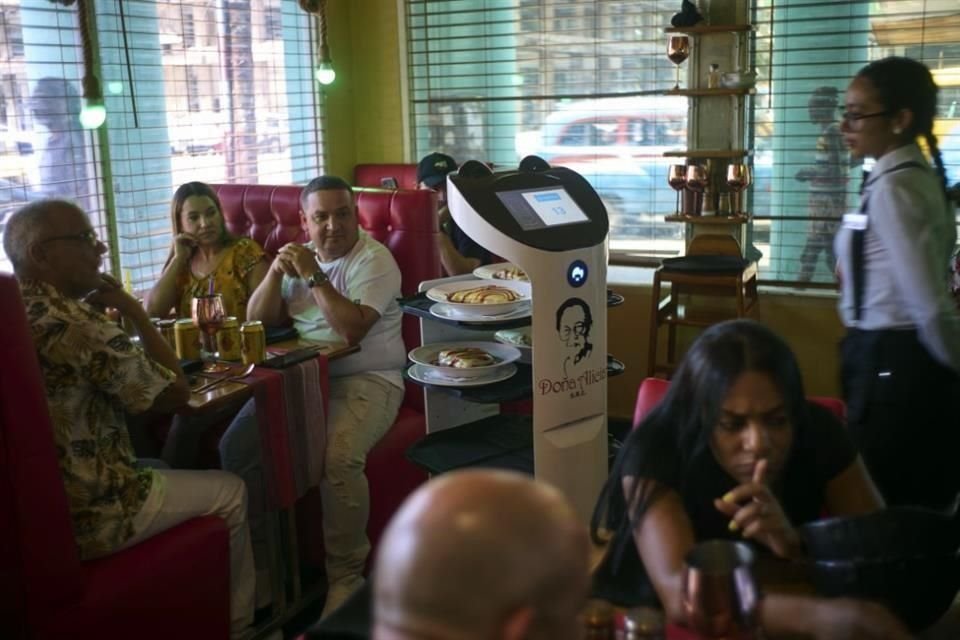 Clientes observan cómo un robot llega con su comida al restaurante 'Doña Alicia' en La Habana.