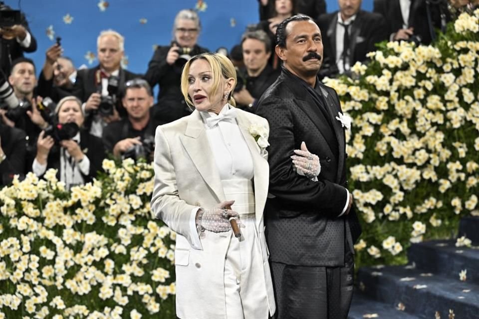 Madonna lució un look monocromático, compuesto por un traje blanco satinado con boutonniere, una blusa abotonada y guantes de encaje. Fue cortesía de Tom Ford, diseñado por Haider Ackermann (der.).