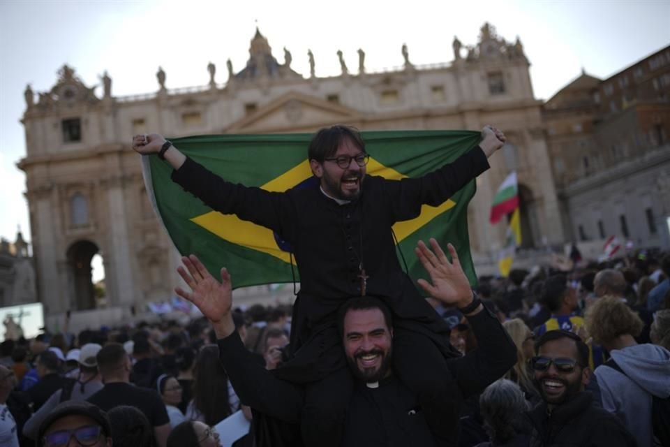 Clérigos celebran tras la revelación del humo blanco desde la chimenea de la Capilla Sixtina.