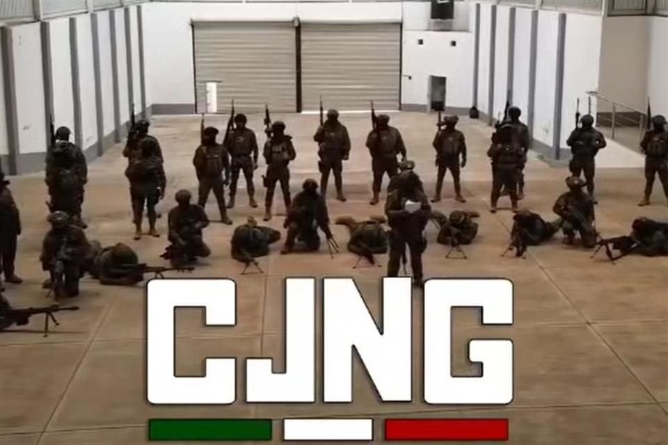 Alrededor de 35 hombres, fuertemente armados, aparecen en una especie de bodega, en donde uno de ellos hace el señalamiento.