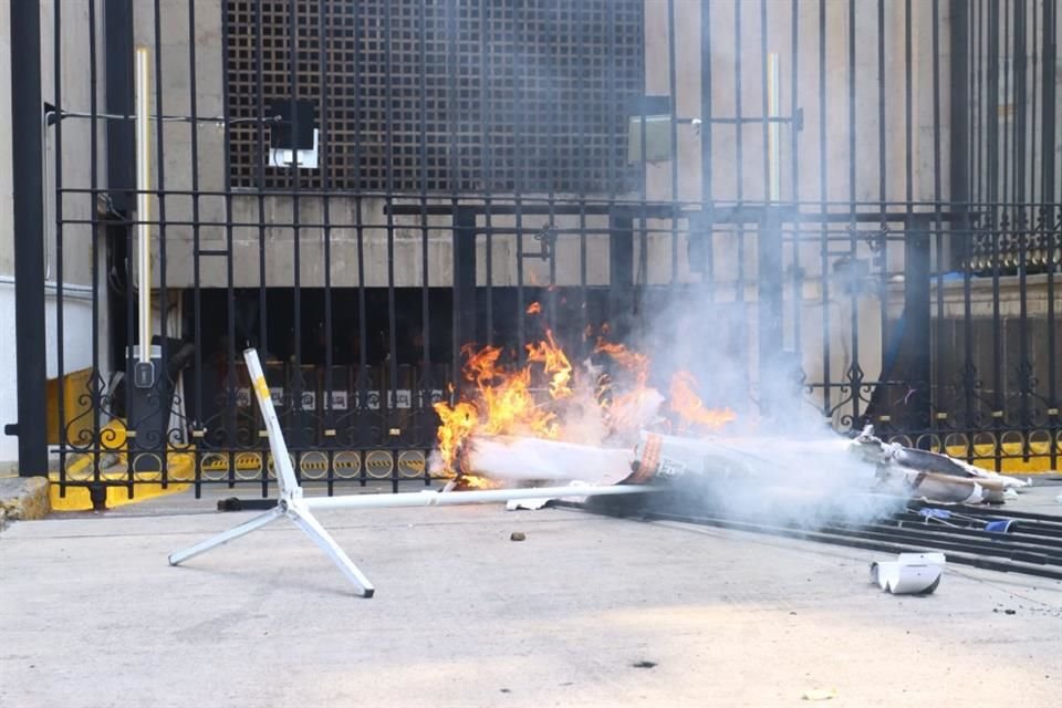 Maestros de la CNTE quemaron cartones encima de una reja afuera del estacionamiento de Segob, donde un grupo de representantes se reúne con autoridades federales.