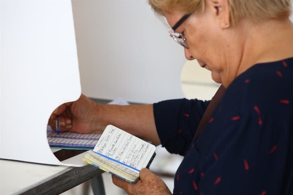 Con ayuda de anotaciones, una mujer emitió su voto en la casilla de la sección 3121, S1 especial, en Paraísos de El Colli, en Zapopan.